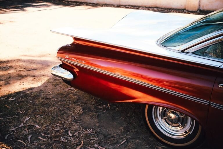 Vintage red Chevrolet Biscayne car in sunlight showcasing elegant tail fins and chrome details.