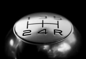 Detailed close-up of a stainless steel gear shift knob against a black background.