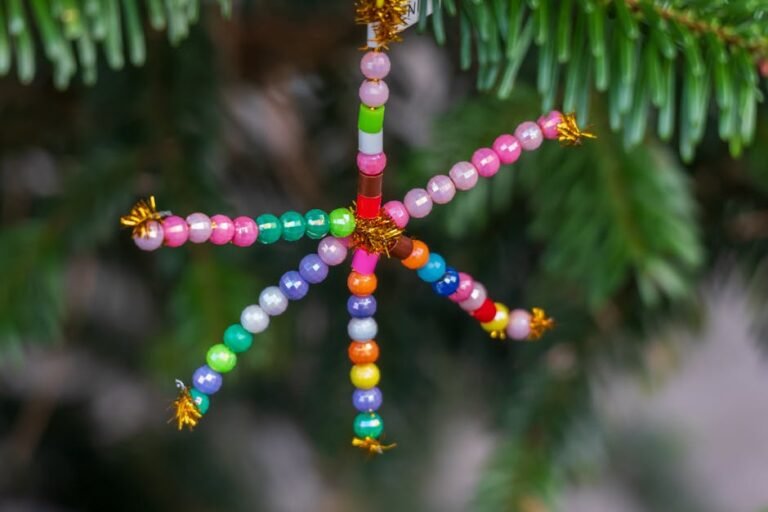 Bright and cheerful bead star ornament hangs on a lush green pine tree branch.