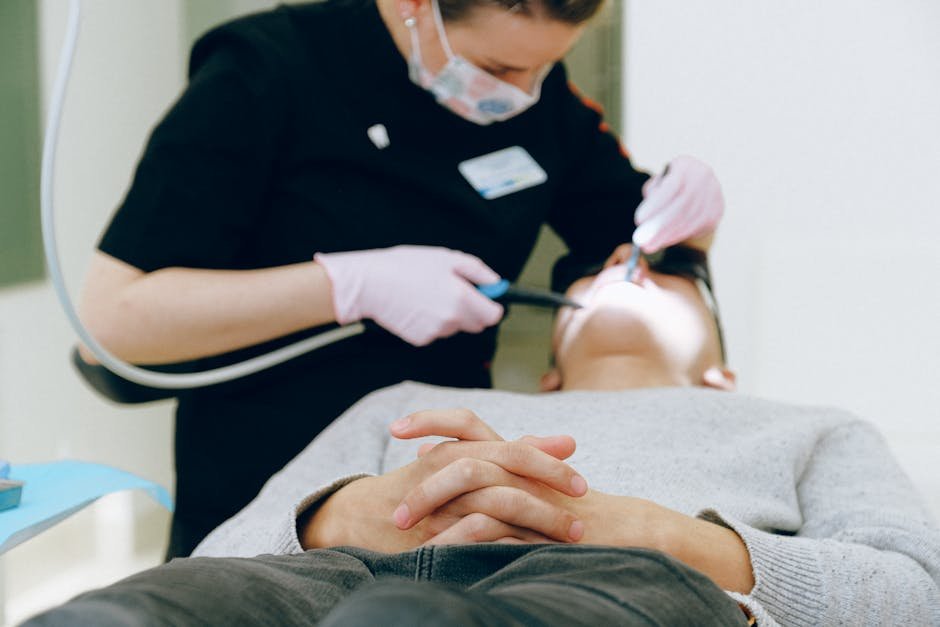Patient receiving dental care from a dentist wearing gloves and mask in a clinic.