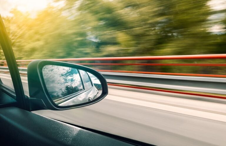 Side mirror view capturing high-speed travel on an expressway with motion blur effect.