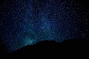 A stunning view of the star-filled night sky with silhouetted mountains beneath, offering a serene and captivating scene.