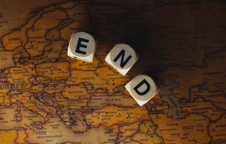 Close-up of dice spelling 'END' placed on a map of Europe, symbolizing finish line or travel completion.