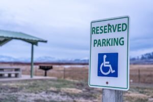 Close-up of a reserved parking sign by a scenic picnic area with distant mountains.