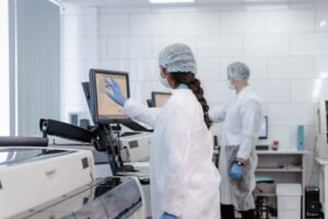 Two scientists in protective gear working with lab equipment in a high-tech laboratory.